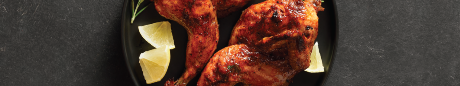 Roasted chicken with herbs and lemon slices on a plate